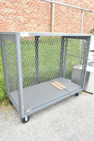 Gray metal cart with mesh sides on commercial casters, used condition. Ideal for transport and storage.