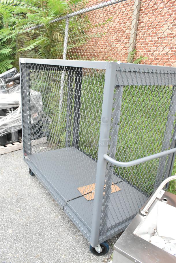 Gray metal cart with mesh sides on commercial casters, outdoor setting, minimal wear, sturdy handle, visible cardboard piece.