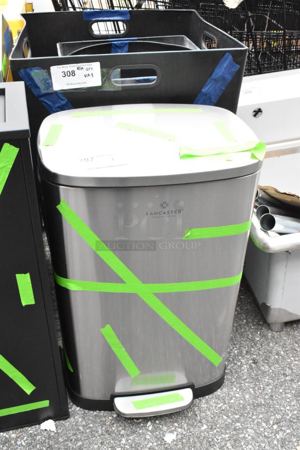 Brand new Lancaster trash can with chrome finish, visible scratch and dent, green tape, and Lancaster logo displayed.