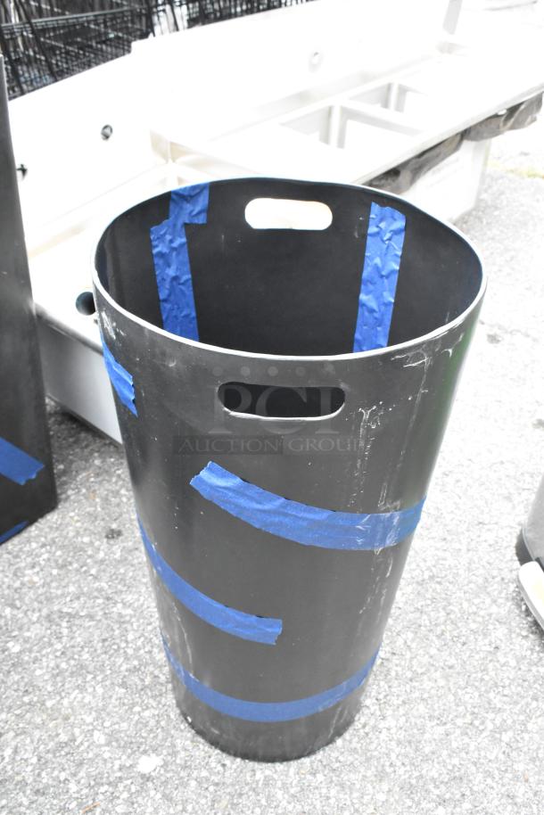 Black trash can with blue tape, showing minor scratches. Brand new, sold in a lot of three. Sturdy handles, durable material.