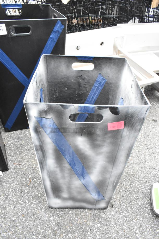 Three new black trash cans with scratches and blue tape, featuring cut-out handles and a red price tag labeled "1001".