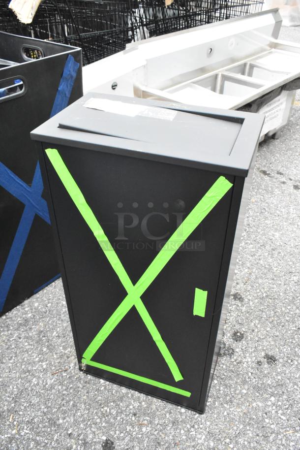 Brand new black and chrome trash can with green tape marks indicating scratches and dents, auctioned for 2 times bid.
