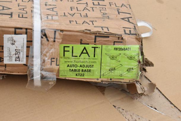 Box containing FLAT Auto-Adjust Table Base KT22. Visible labels indicate model FBT2068AQ1. Box shows wear.