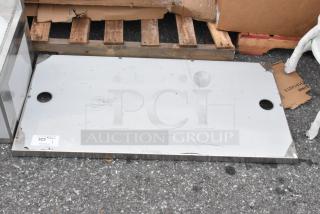 Brand new stainless steel panel with scratches and dents, flat rectangular shape, visible tag with lot number 323.