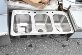 Brand new stainless steel 3 bay drop-in sink with minor scratches. Includes pre-drilled faucet holes and visible label indicating model.