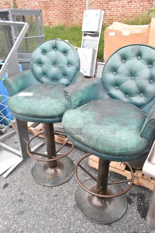 Two bar height chairs with tufted green upholstery and dark bases. Some wear visible on the fabric and bases.