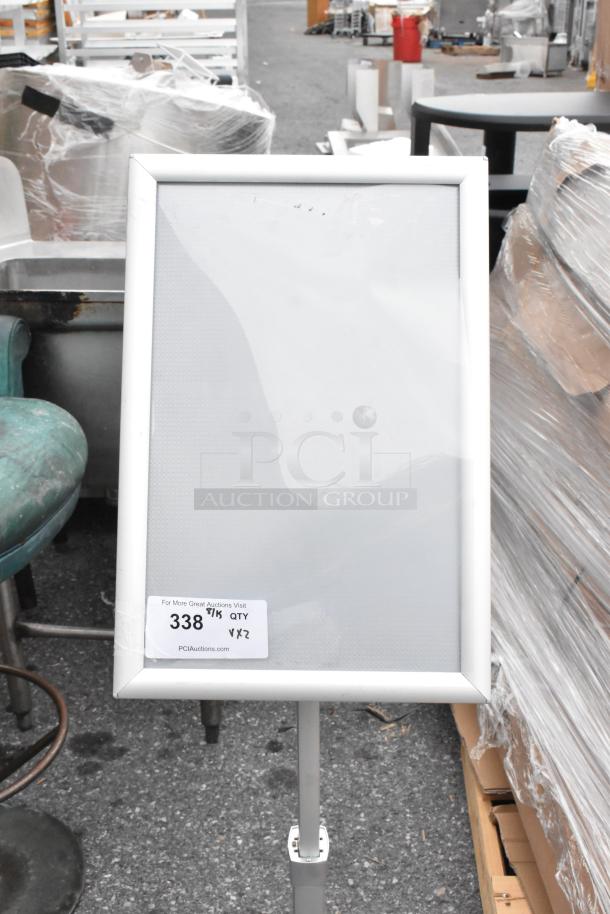 White framed sign with adjustable stand, label reads "For More Great Auctions Visit, 338," quantity two. Good condition.