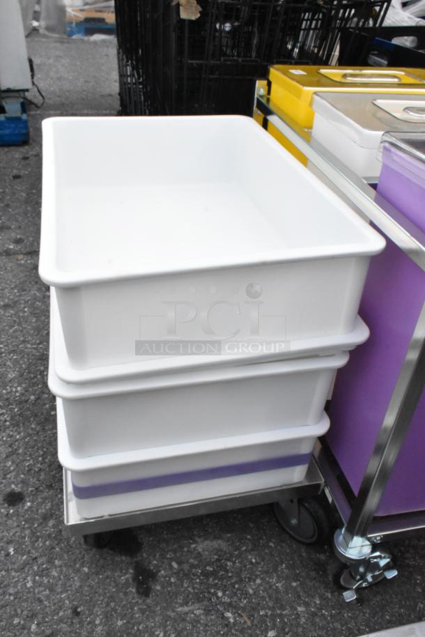 Two white poly dough bins on a wheeled dolly, alongside three poly ingredient bins in a frame, for auction.