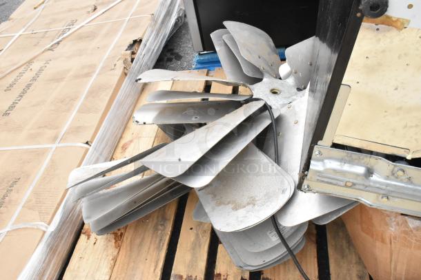 Assorted metal fan blades in various conditions, bundled on a wooden pallet. Includes mixed industrial parts.