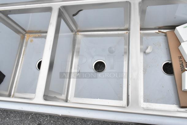 Brand new Regency 600S31824224 stainless steel 3 bay sink with dual drain boards, no legs. Some scratches and dents visible.