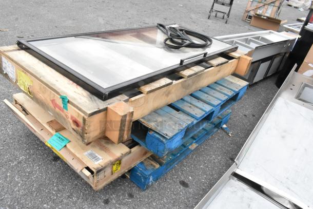 Brand new scratch and dent items, including a slimline black 3-pane reflective door and a chrome 2-pane door, on pallets.
