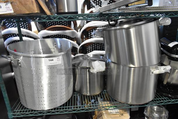 Three stainless steel stock pots and one perforated steam/colander pot, new condition. Label shows item 144, quantity 4.
