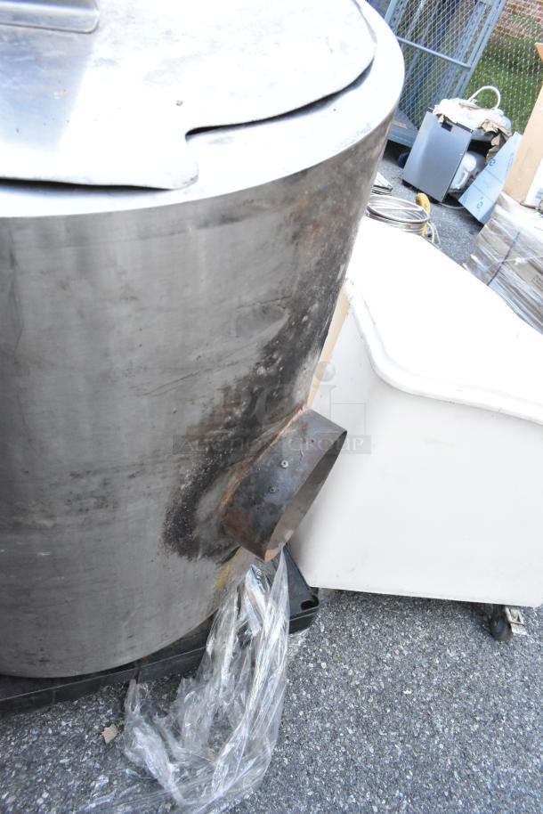 Large stainless steel kettle with a curved lid, visible signs of use and wear, and an attached metal spout.
