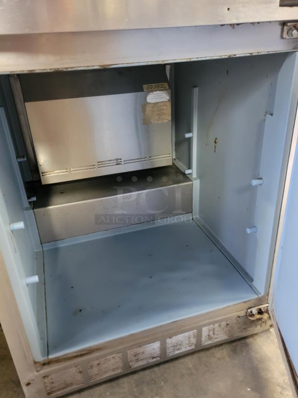 Delfield Model UC4427N-6M-DD1 refrigerated prep table; features top prep area, lower refrigerated compartment; visible wear.