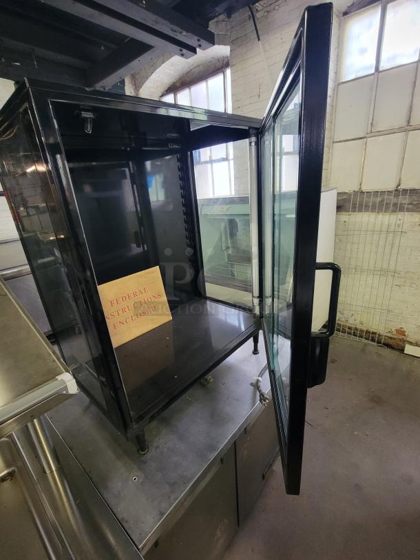 Federal Industries SB28SS lighted display case with black frame and clear glass door, ideal for showcasing products. Instructions included.