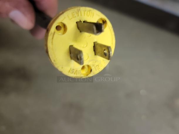 Yellow Leviton electrical plug with three prongs, marked "15A 125V."