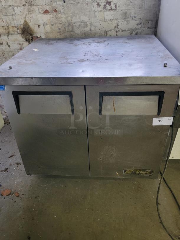True TUC-36-34 undercounter commercial refrigerator with dual doors, stainless steel, visible wear, ideal for food storage.