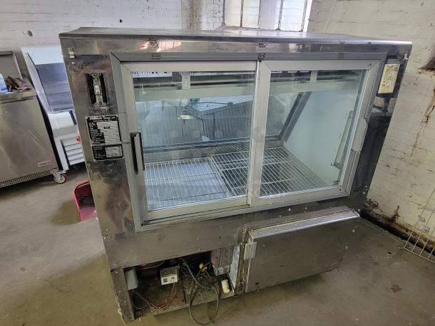 Pinnacle SC734 refrigerated display case, ideal for cafés. Features include double glass doors, metal shelving, and temperature controls.