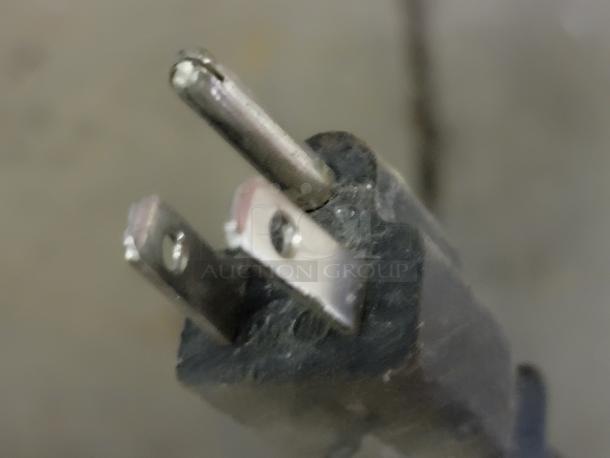 Close-up of an electrical plug with visible metal prongs, likely from the Electrolux FFBC4622QS-1 wine chiller.