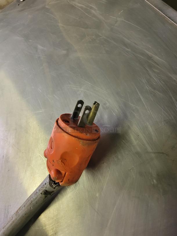 An orange electrical plug on a stainless steel surface, related to a Metro C563-SFS-U heated holding cabinet.