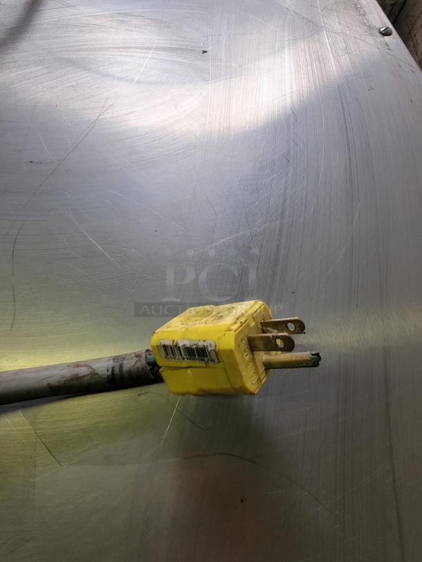 Yellow power plug attached to a Metro C563-SFS-U heated holding cabinet, showcasing the utility connection on a metallic surface.