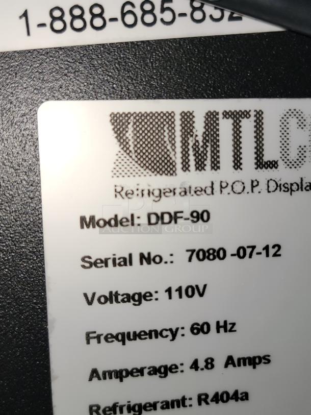 Brand new RMTLC DDF-90 refrigerated P.O.P. display label showing model, serial number, voltage, and refrigerant details.