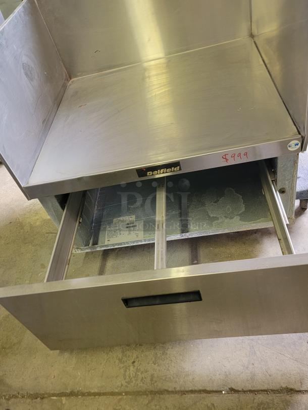 Delfield stainless steel equipment stand, model F17DD32, with spacious top, storage drawer, and visible $999 price tag.