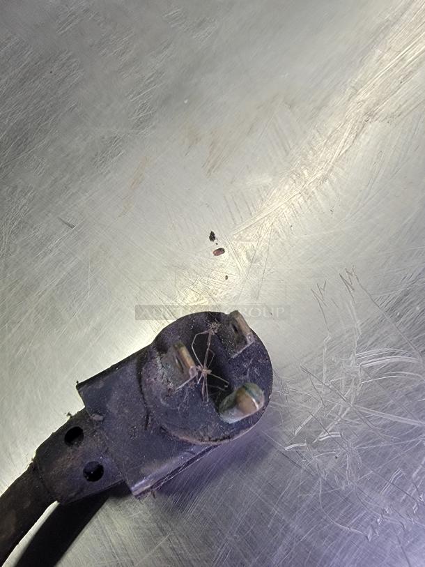 Dusty plug on a scratched metal surface from a True TUC-36-34 commercial refrigerator, indicating wear.