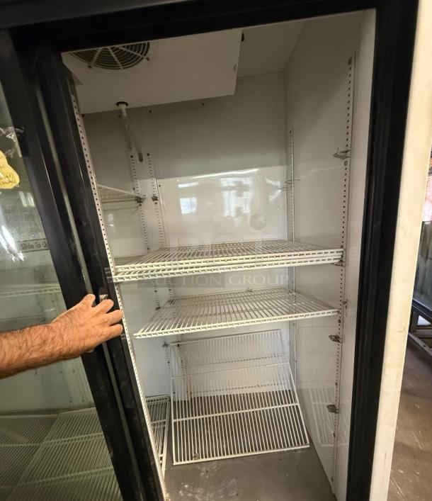 TRUE GDM-69 glass door commercial refrigerator with three sliding doors, adjustable shelves, and visible interior fan.