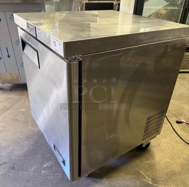 Bison BUR-27 commercial undercounter refrigerator. Stainless steel finish, single door, caster wheels, serial tag visible.