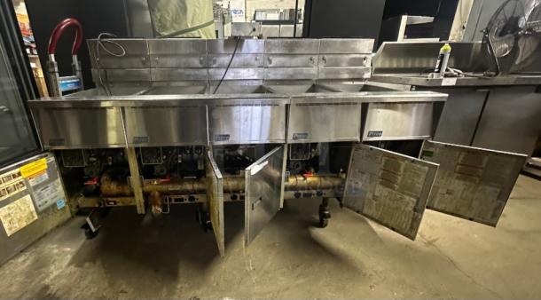 Pitco SSHBN55 Fryer Battery with dump and filter system. Ideal for high-volume use. Stainless steel, open cabinet doors.