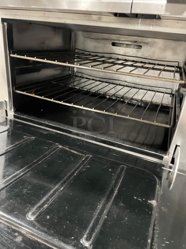 Vulcan commercial stainless steel oven with wired rack, part of an 8-burner range/oven combo, clean and spacious interior.