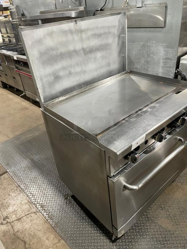 Migali commercial stainless steel natural gas flat griddle range/oven combo with back splash and wired racks on casters.
