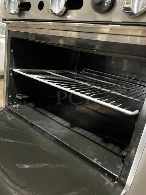 Migali commercial stainless steel natural gas flat griddle range/oven combo with wired oven racks, back splash, on casters.