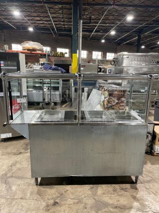 Custom stainless steel 4-well steamtable with sneeze guard, natural gas powered, includes hotel pans, on sturdy legs.