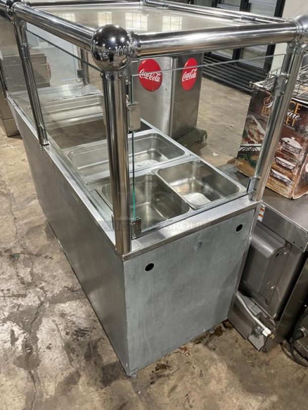 Custom stainless steel steam table with four wells, natural gas powered, serve-over sneeze guard, includes hotel pans, on legs.