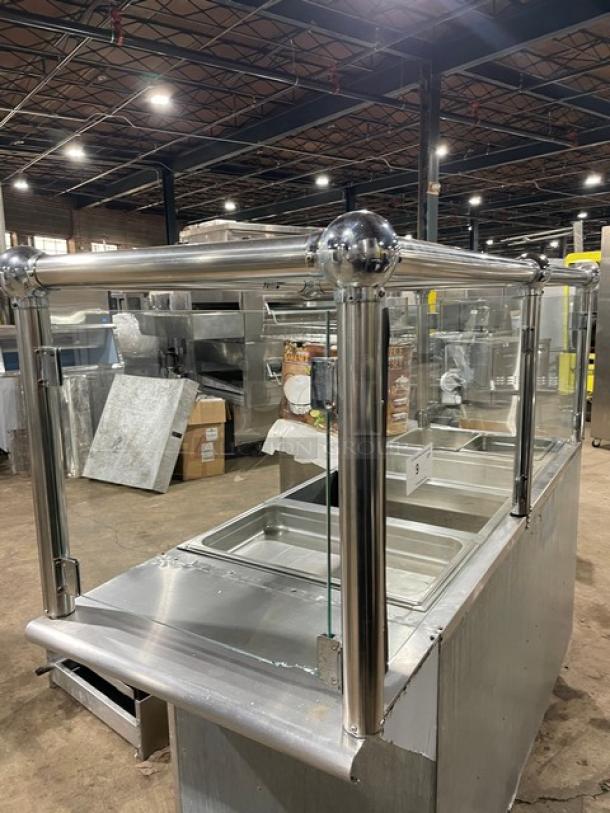 Custom stainless steel 4-well hot food steamtable with natural gas power, fancy sneeze guard, and hotel pans; on legs.