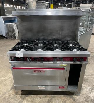 Vulcan stainless steel 8 burner gas range with oven, backsplash, overhead salamander shelf, cabinet storage, and casters.