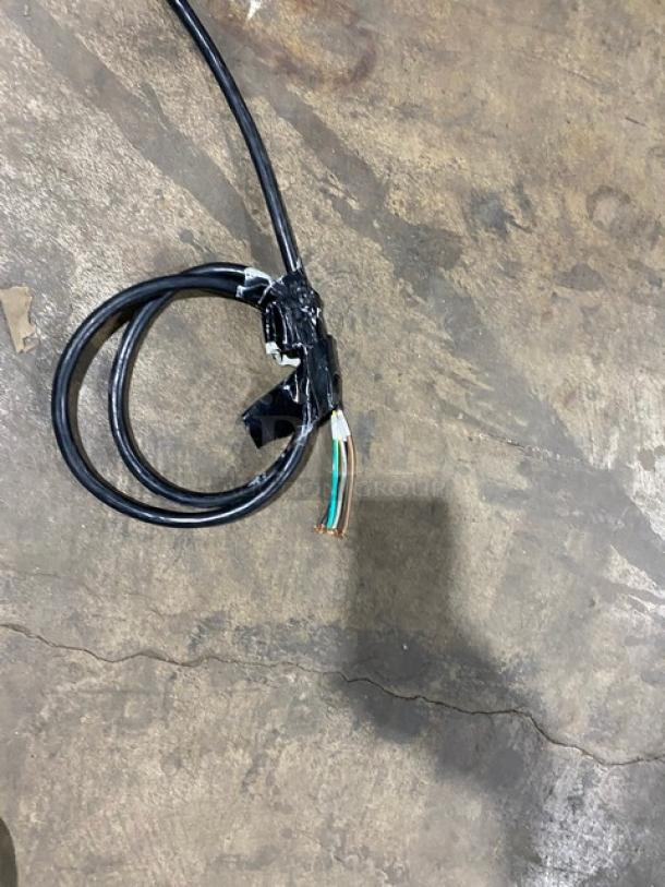 Black electrical power cord with exposed colored wires and tape, on a concrete floor.