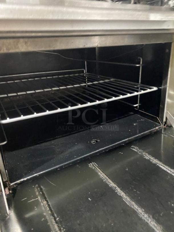 Therma Tek stainless steel 10-burner range/double oven combo with wired racks, backsplash, and casters, in good condition.