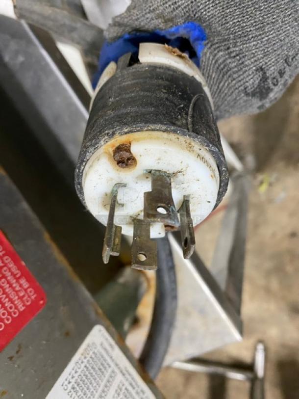 Convotherm combi oven power plug, showing wear. Stainless steel body partially visible with attached equipment tag.