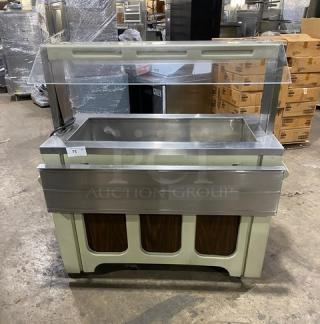 Custom buffet-style commercial stainless steel cold food salad bar with sneeze guard and folding tray slide, on casters.