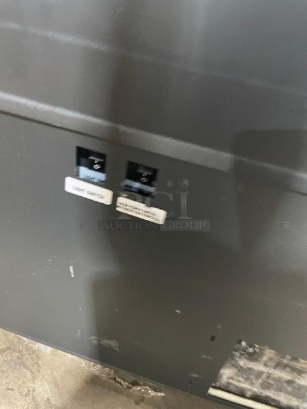 Structural Concepts SBZ6652DR black refrigerated merchandiser, 220V 1 Phase, on legs, light and power switches visible.