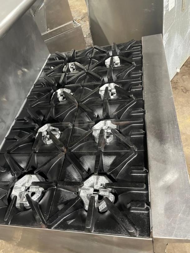 U.S. Range stainless steel 8-burner range with double oven, backsplash, overhead salamander shelf, and wired oven rack. In good condition.