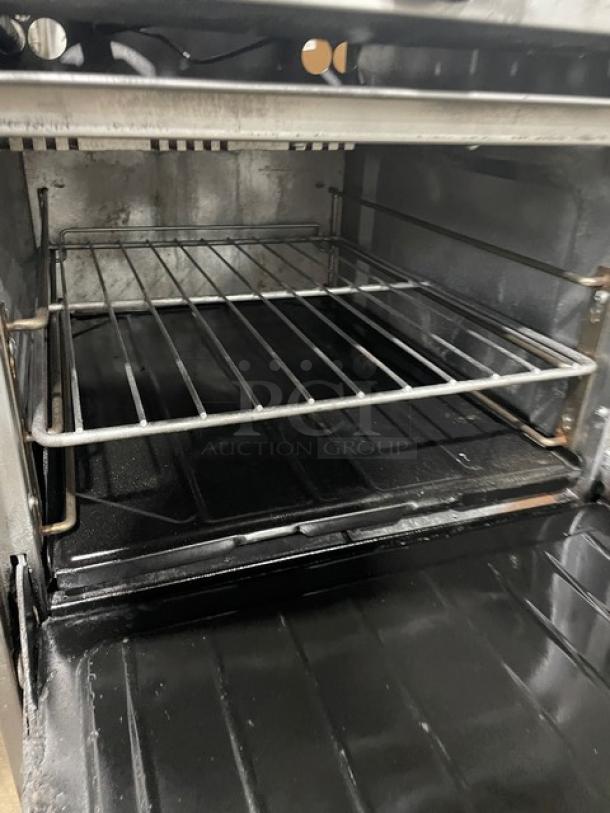 U.S. Range stainless steel 8-burner range, double oven with wired rack, backsplash, overhead salamander shelf, on legs.
