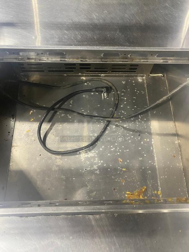 Turbo Air MST-28-711S refrigerated prep table interior, stainless steel, with power cable, minor debris visible.