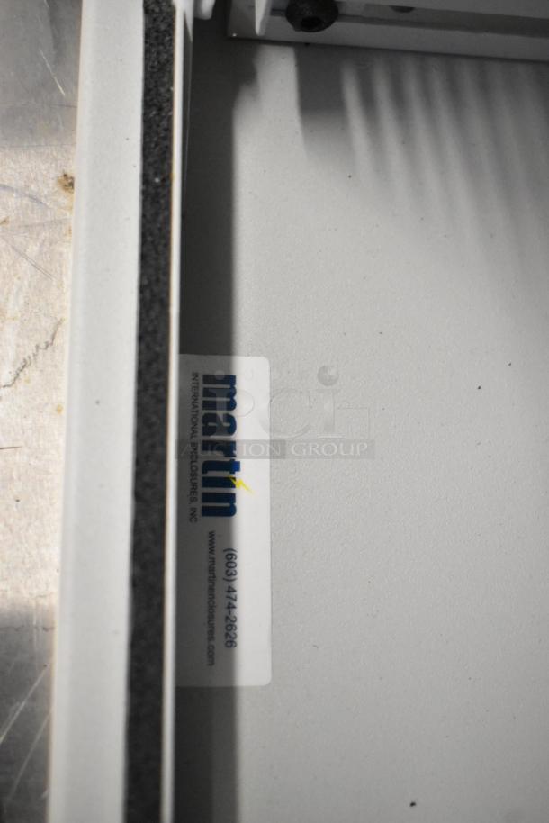 Brand new Martin white metal enclosure with a visible label indicating "Martin International Enclosures, Inc." and contact information.