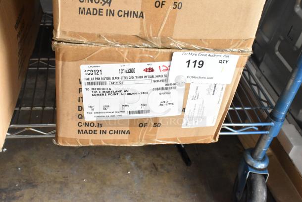 Box of 12 Vollrath 9.5" paella pans, black steel, dual handles. "Scratch and Dent" condition. Labels show shipping info.