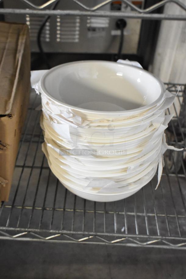 Stack of new white poly bowls on a metal shelf, packaged with protective paper, part of an auction lot including spoons and plates.