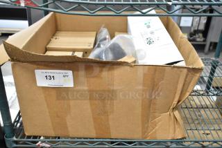 Cardboard box containing 9 new scratch and dent items including Tripp Lite N252-048 rack mount, PFA137 camera mounts. Item tag reads "131 QTY X9".